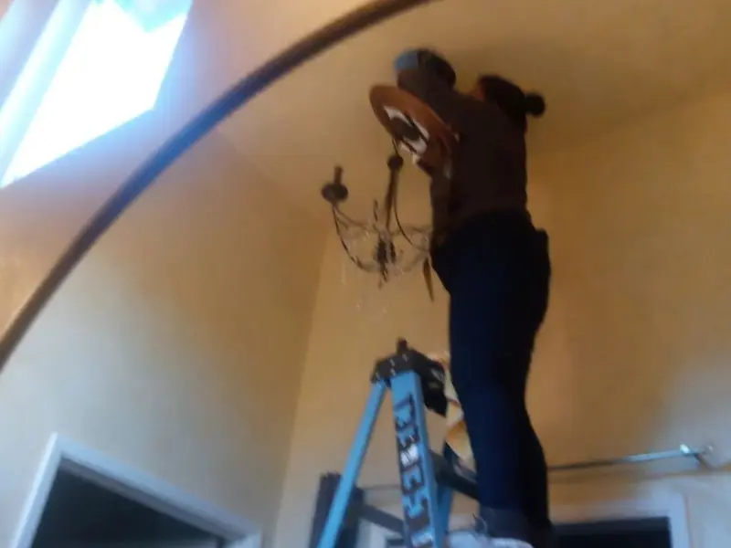 Electrician installing a chandelier in a Taos residence